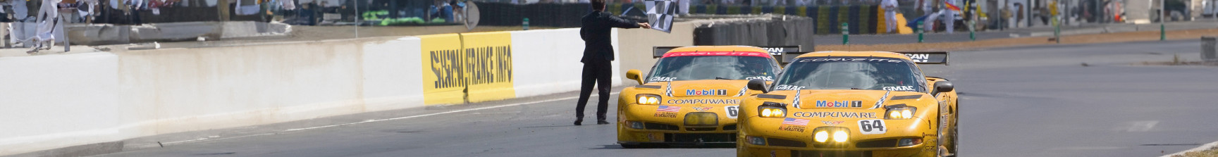 two corvette racing cars crossing the line at Le Mans from the front angle